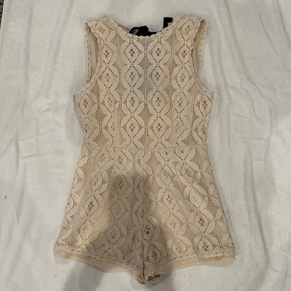 Off white romper with black ties on the back Size M.